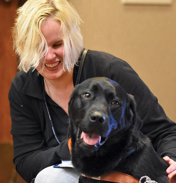 Young lady petting her black lab guide dog